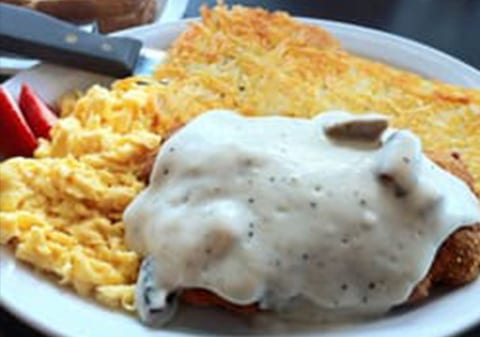 A plate of food with chicken and rice covered in gravy.