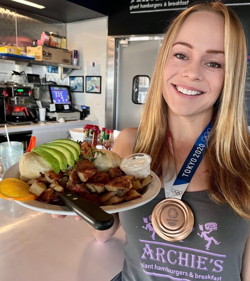 A lady wearing an Olympics medal and holding a plate of food